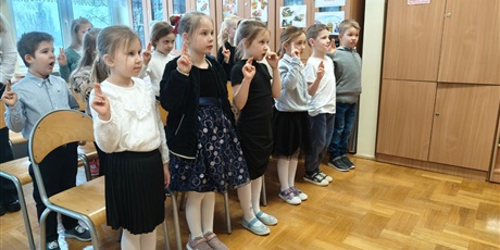 Powiększ grafikę: Uczniowie podczas pasowania na czytelnika w bibliotece.