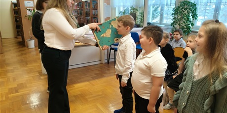 Powiększ grafikę: Pani dyrektor dokonuje pasowania na czytelnika w bibliotece szkolnej.