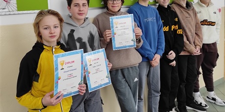 Powiększ grafikę: Zbiorowe zdjęcie uczniów z dyplomami za konkurs na korytarzu szkolnym.