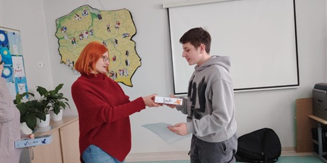 Powiększ grafikę: Uczeń otrzymuje nagrodę za konkurs od wicedyrektora szkoły w sali lekcyjnej.