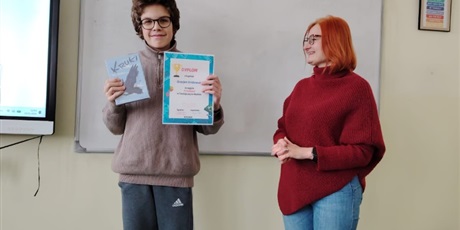 Powiększ grafikę: Uczeń otrzymuje nagrodę za konkurs od wicedyrektora szkoły w sali lekcyjnej.