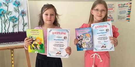 Powiększ grafikę: Uczennice z dyplomami i nagrodami za konkurs czytelniczy  na korytarzu szkolnym.